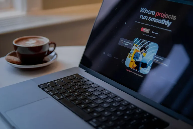 Laptop egy landing oldallal a képernyőn, mellette egy csésze kávé az asztalon